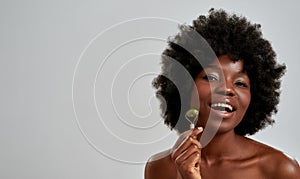 Portrait of excited young african american woman with perfect glowing skin smiling at camera while massaging her face