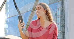 Portrait of excited young brazilian woman receiving good news on cellphone outdoors. Smiling lady enjoys success on smartphone out