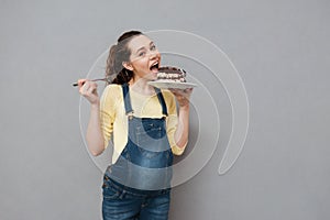 Portrait of an excited young pregnant woman eating chocolate cake