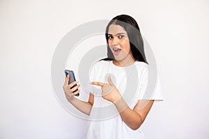 Portrait of excited young woman pointing at mobile phone