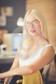 Portrait of an executive professional mature businesswoman sitting on office desk