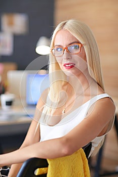 Portrait of an executive professional mature businesswoman sitting on office desk