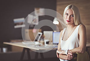 Portrait of an executive professional mature businesswoman sitting on office desk