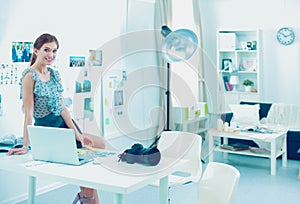 Portrait of an executive professional mature businesswoman sitting on office desk in casual and smiling