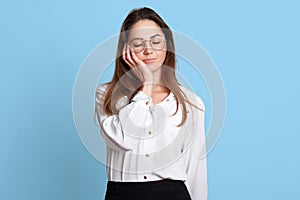 Portrait of exhausted sleeping businesswoman holding her head with closed eyes on right hand. Attractive young female enjoys short