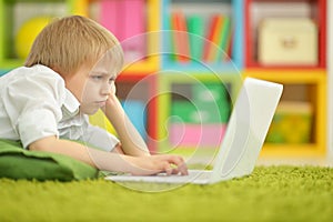 Exited boy using laptop while lying on floor