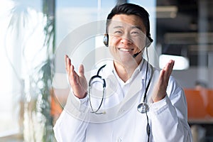 Portrait of an experienced Asian doctor, looking at the camera and having fun talking to the patient, smiling amicably and