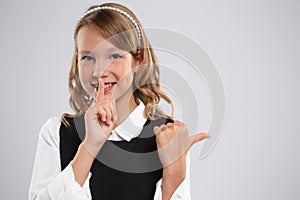 Portrait of an expressive beautiful young girl student who put her finger to her lips to create a gesture of silence