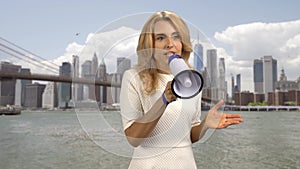 Portrait of an expressive blonde woman giving a speech in megaphone.