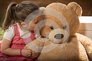 Portrait of expressive little girl hugging her toy bear