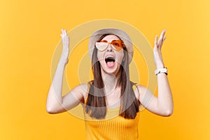 Portrait of expressive screaming sad upset woman in orange glasses spreading hands, keeping mouth wide open, looking up