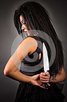 Portrait of an expressive young woman holding a big knife to her photo