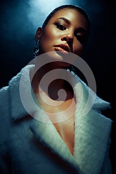 Portrait of an extraordinary beautiful stylish metis young woman with perfect smooth glowing mulatto skin in a fur coat