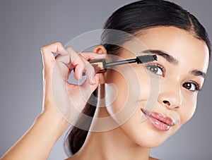 Portrait, eyelash and brush for makeup, mascara and beauty with girl with grey studio background. Face, eyes and salon