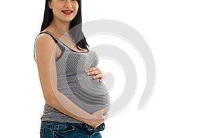 Portrait without eyes of cheerful brunette pregnant woman touching her belly isolated on white background