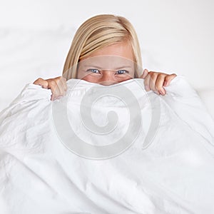 Portrait, eyes and happy woman in a bed with blanket, hiding or waking up playful in her home. Morning energy, face and