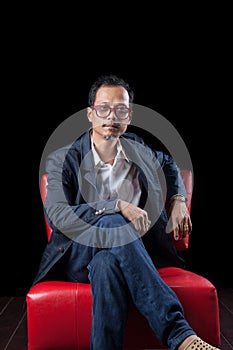 Portrait face of 45s years old asian man sitting on red sofa in
