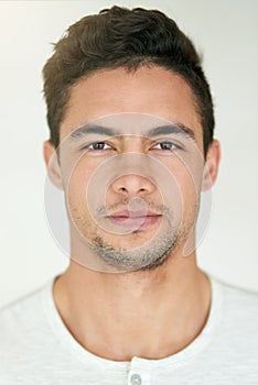 Portrait, face and headshot of man in studio, isolated white background and posing with casual attitude. Handsome young photo