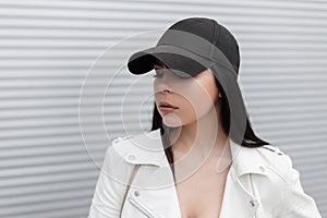 Portrait of the face of a pretty beautiful brunette young woman in a stylish black baseball cap in a fashionable