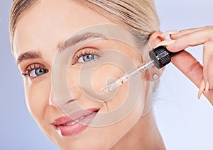 Portrait, face and skincare of woman with serum in studio isolated on a blue background. Dermatology cosmetics, beauty