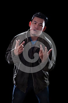 portrait face of young asian man acting like a rocker man standing against dark background