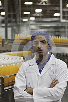 Portrait of factory worker standing with arms crossed at bottling plant