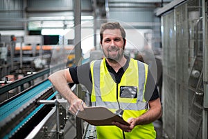 Portrait of factory worker standing with clipboard