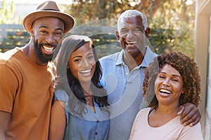 Portrait of Family With Adult Parents With Grown Up Son And Daughter Relaxing In Garden At Home