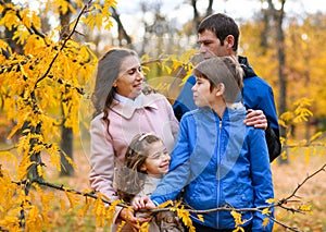 Portrait of a family in an autumn park. Happy people pose against the background of beautiful yellow trees. They hug and are happy