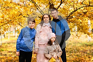 Portrait of a family in an autumn park - happy people posing against a background of beautiful yellow trees
