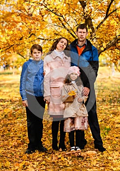 Portrait of a family in an autumn park - happy people posing against a background of beautiful yellow trees