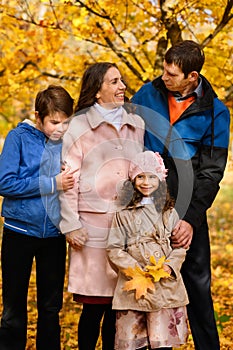 Portrait of a family in an autumn park - happy people posing against a background of beautiful yellow trees