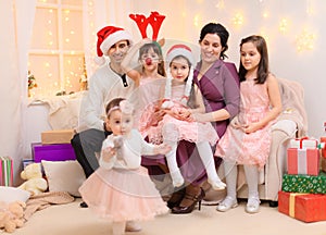 Portrait of a family celebrating new year or christmas holiday, parents and children, dressed in santa helper hat, sitting on a
