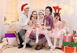 Portrait of a family celebrating new year or christmas holiday, parents and children, dressed in santa helper hat, sitting on a