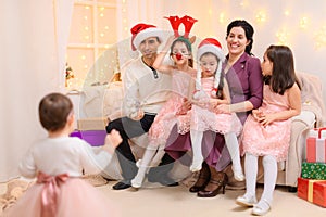 Portrait of a family celebrating new year or christmas holiday, parents and children, dressed in santa helper hat, sitting on a