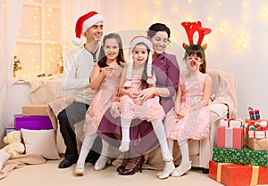 Portrait of a family celebrating new year or christmas holiday, parents and children, dressed in santa helper hat, sitting on a