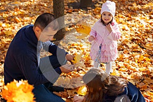 Portrait of a family with children in an autumn city park, happy people walking together, playing with yellow leaves, beautiful