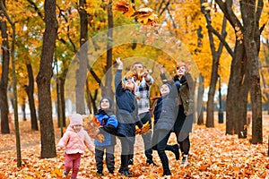 Portrait of a family with children in an autumn city park - happy people walking together, they toss the leaves, beautiful nature