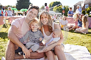 Portrait Of Family With Children Sitting On Rug At Summer Garden Fete