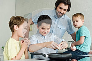 portrait of family cooking eggs for breakfast together in kitchen