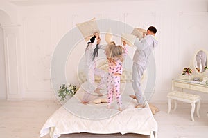 Portrait of family fighting pillows, jumping on bed together in