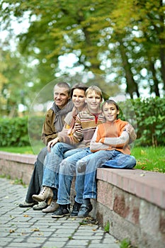 Portrait of family of four sitting in park