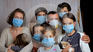 Portrait of a family having six children in protective medical masks on a background of a wooden wall. They look at the