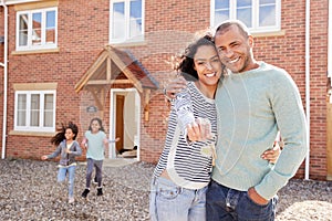 Portrait Of Family Holding Keys Standing Outside New Home On Moving Day