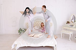 Portrait of family jumping on bed looking at camera together in photo