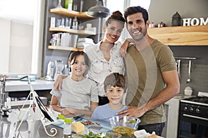 Portrait Of Family In Kitchen Following Recipe On Digital Tablet
