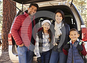 Portrait family outdoors standing at the open back of car