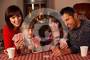 Portrait Of Family Playing Cards By Cosy Log Fire