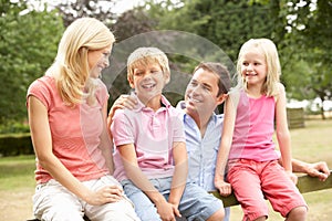 Portrait Of Family Sitting On Fence In Countryside