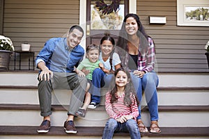 Portrait Of Family Sitting On Steps in Front Of House